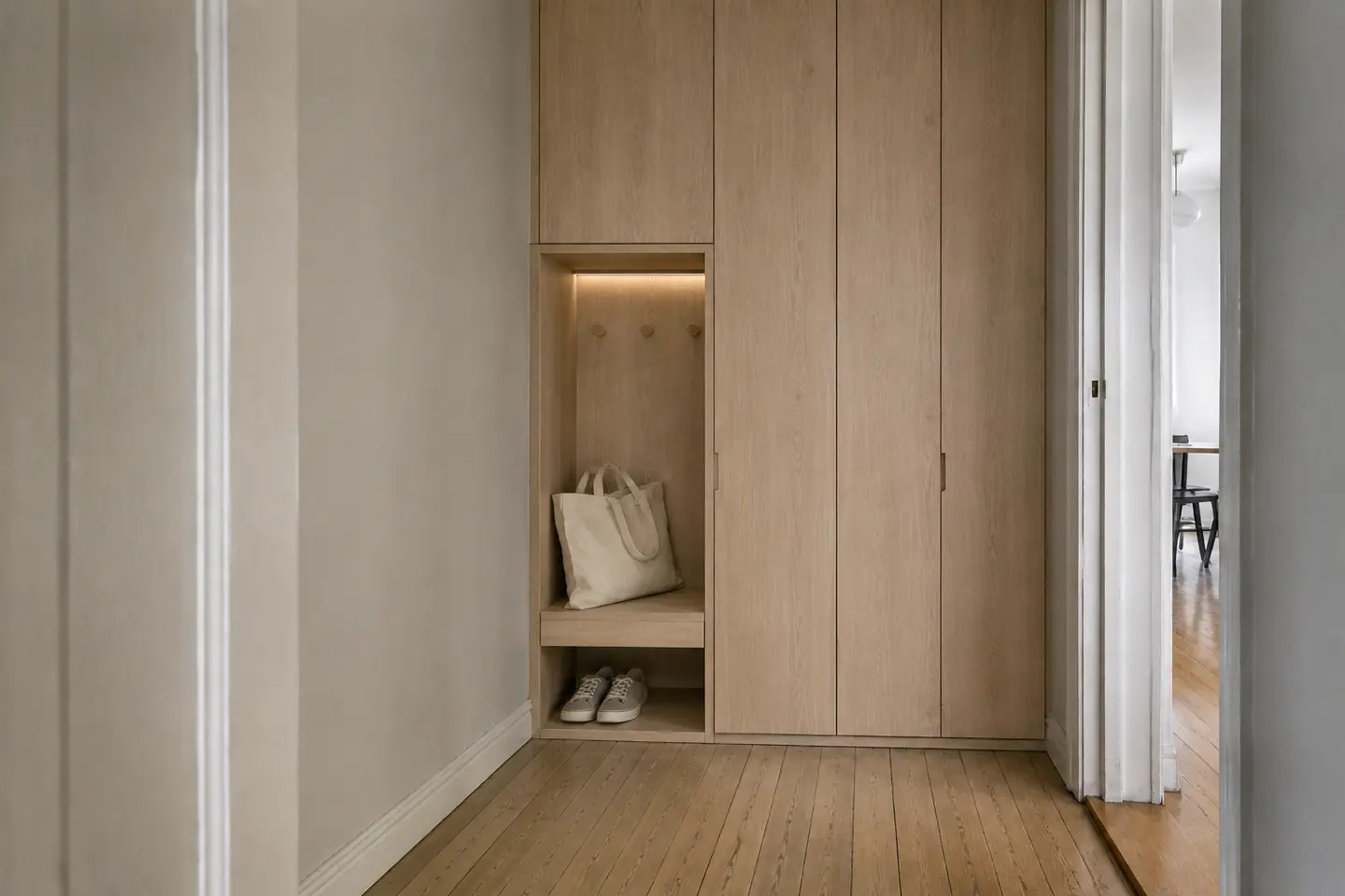 The same entrance after work, with a fitted wardrobe, oak bench and integrated lighting